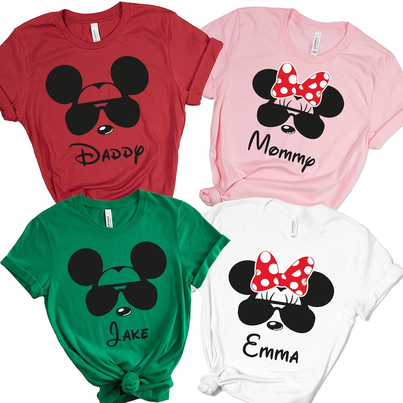 K&ouml;nnte beinhalten: Vier kurz&auml;rmelige T-Shirts in Rot, Rosa, Gr&uuml;n und Wei&szlig;. Jedes Shirt zeigt ein Cartoon-Mausgesicht mit Sonnenbrille. Das rote Shirt sagt "Daddy", das rosa Shirt sagt "Mommy", das gr&uuml;ne Shirt sagt "Jake" und das wei&szlig;e Shirt sagt "Emma".