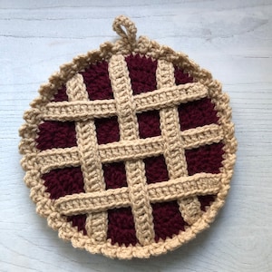 May include: A crocheted pie pot holder with a brown crust and a burgundy filling. The pot holder has a loop for hanging.