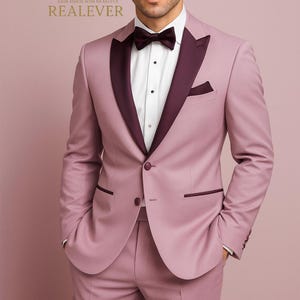 May include: A formal mauve suit with a contrasting burgundy lapel and bow tie. The suit includes a jacket, trousers, and a white dress shirt. The image includes the text "Look Iconic with REALEVER" and the brand name "REALEVER".