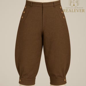 Può includere: Pantaloni alla zuava marroni, al ginocchio, con vita alta e dettagli di bottoni. I pantaloni hanno una forma arrotondata e sono realizzati in tessuto tinta unita. L'indumento presenta bottoni laterali e sui polsini.