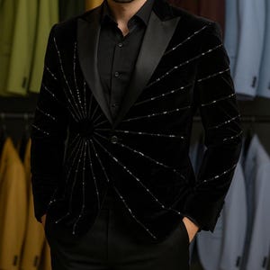 May include: A black velvet blazer with a radiating sequin design. The blazer has a satin lapel and is paired with a black button-down shirt and black pants. The word "REALEVER" is visible in the background.