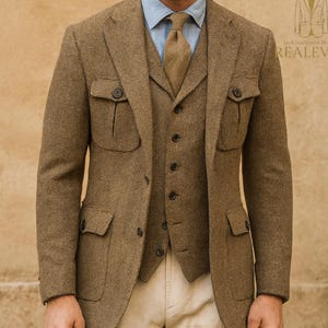 May include: A three-piece brown tweed suit with a matching cap. The suit includes a jacket with four pockets, a vest, and a light blue dress shirt with a brown tie. The pants are khaki-colored.