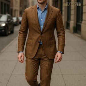 May include: A man wearing a brown suit with a blue button-down shirt. The suit jacket is buttoned, and the pants are tailored. The image includes the text "REAL EVER" and a logo.