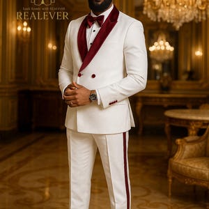 May include: Ivory double-breasted suit with a burgundy velvet lapel and trim. The suit features a matching burgundy bow tie and a burgundy stripe down the side of the pants. The image includes the text "REALEVER".