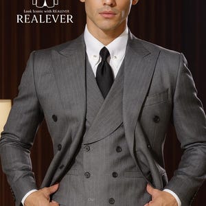 May include: A gray pinstripe suit with a double-breasted jacket, vest, and matching trousers. The suit features a white dress shirt and a black tie. The image includes the text "Look Iconic with REALEVER" and "REALEVER".