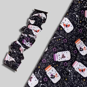 May include: Black watch band with a repeating pattern of jars, butterflies, flowers, and constellations. The jars have orange, purple, and pink lids. The background is black with white stars and constellations.
