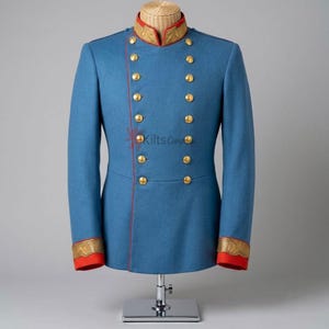 May include: A blue double-breasted jacket featuring a high collar with gold embroidery, red trim, and two columns of gold buttons. The cuffs are red with gold embroidery. The text Kilts Company is visible on the front of the blue fabric.