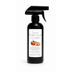 Puede incluir: Una botella de spray de plástico negro que contiene 473 ml de limpiador multiusos. La etiqueta blanca presenta el texto Cinnamon Pumpkin Crunch, una ilustración de una calabaza y un rollo de canela, e instrucciones, incluyendo 16 fl oz.