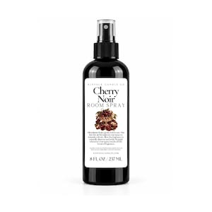 May include: A black plastic spray bottle containing 8 fl oz of Cherry Noir room spray. The white label features the text Kinfolk Candle Co, Cherry Noir Room Spray, an illustration of cherries in a bowl, and usage directions.