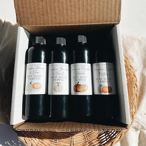 Può includere: Una scatola di cartone contenente quattro flaconi neri di campioni di sapone MOP. Ogni flacone ha un'etichetta bianca con un'illustrazione a tema autunnale e il nome del gusto: Pumpkin Honey & Chai, Pumpkin Bourbon & Vanilla, Cinnamon Pumpkin Crunch e Pumpkin Cookie Butter.