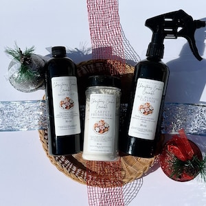 May include: A selection of cleaning products, including mop soap, carpet freshener, and all-purpose cleaner, in black bottles and a jar. The products are labelled "Christmas Cookie Crumble" and are presented in a woven basket with decorative ribbons and accents.