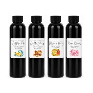 May include: Four black plastic bottles with black screw caps, each featuring a white label with the text Kinfolk Candle Co. Mop Soap Sample. The labels display illustrations of lemons, a beach scene, melon slices, and pink flowers respectively.