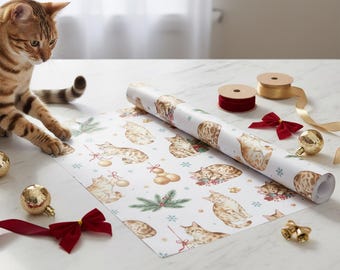 May include: A roll of white wrapping paper featuring a repeating pattern of Bengal cats, Christmas ornaments, and snowflakes. A brown and tan cat sits near the paper. Red and gold ribbons, bells, and ornaments are also present.