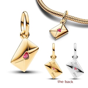 May include: Gold-toned envelope charm with a red heart-shaped gem. The charm has a loop for attaching to a bracelet or necklace. The back of the charm has the text "to: my love xoxo".