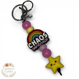 May include: A keychain with a silver clasp, pink and yellow beads, and a charm that says "CHAOS coordinator" with a rainbow design. A yellow star charm with a smiling face is also attached.