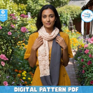 May include: A woman wearing a light beige and gray crochet scarf. The scarf has a detailed openwork design and is draped around the neck. The image also includes text that says "DIGITAL PATTERN PDF".