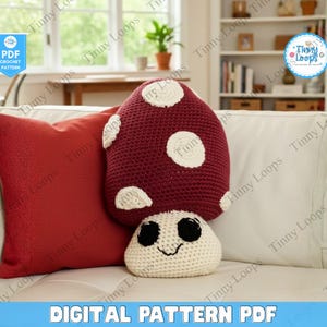 May include: A burgundy mushroom-shaped crochet pillow with white spots and a cream-colored base with a smiling face. A red square pillow is to the left. The words "DIGITAL PATTERN PDF" are at the bottom.