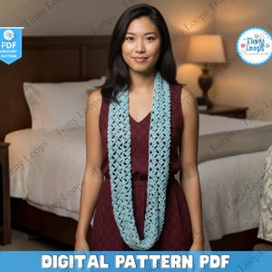 May include: A light blue crochet infinity scarf is worn by a person. The scarf has an open, lacy design. The image also includes the text "DIGITAL PATTERN PDF" and a logo that says "Tinny Loops".