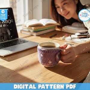 May include: A mug of coffee with a crocheted cozy, featuring a white star design and a button closure. A laptop and books are on a wooden desk. The text "DIGITAL PATTERN PDF" is at the bottom.