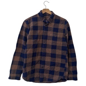 May include: A long-sleeved plaid shirt with a brown and blue checkered pattern. The shirt has a button-down collar and a button front.
