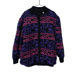 May include: A black and purple patterned cardigan with a zipper closure. The cardigan has a pink and purple geometric design.