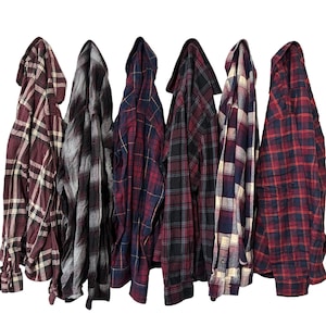 May include: Six plaid shirts in various colors and patterns, including red, black, white, and blue. The shirts are hanging on a white background.