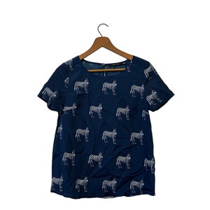 May include: A navy blue short-sleeved shirt with a white zebra print.