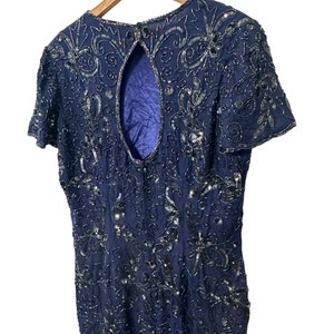 May include: A navy blue sequined dress with a keyhole back. The dress is covered in a floral pattern and has short sleeves.