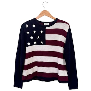 Könnte beinhalten: Ein marineblauer Langarm-Pullover mit einem weißen und burgunderroten amerikanischen Flaggenmuster.