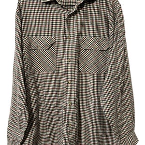 May include: A long-sleeved plaid shirt with a button-up front and two chest pockets. The shirt is in a black, red, and green plaid pattern. The label on the shirt reads "The Bearded Bee".