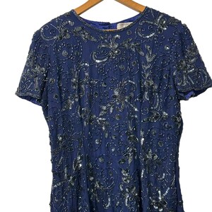 May include: A navy blue sequined dress with a floral pattern. The dress has short sleeves and a round neckline. The dress is made of a soft, flowing fabric and is perfect for a special occasion.