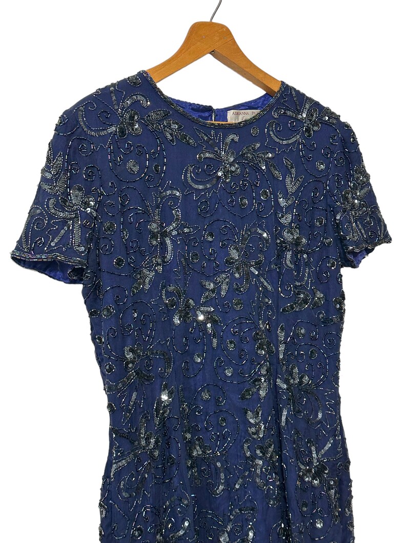 May include: A navy blue sequined dress with a floral pattern. The dress has short sleeves and a round neckline.