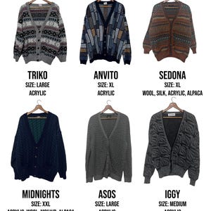 May include: A collection of six button-down cardigans in various colors and patterns, displayed on wooden hangers. The cardigans include geometric and abstract designs, with text labels indicating brand names, sizes, and materials like acrylic, wool, and alpaca.