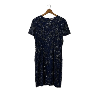 May include: A navy blue sequined dress with short sleeves and a round neckline. The dress is covered in silver sequins and has a fitted silhouette.