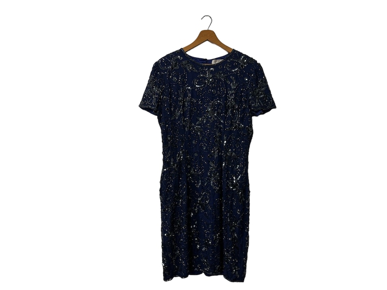 May include: A navy blue sequined dress with short sleeves and a round neckline. The dress is covered in silver sequins and has a fitted silhouette.