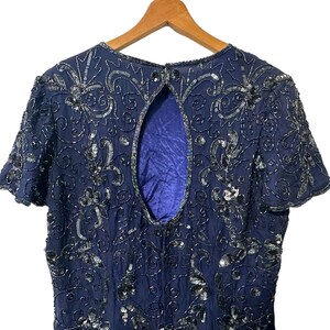 May include: A navy blue sequined dress with a low back and short sleeves. The dress is covered in intricate floral patterns and sequins.