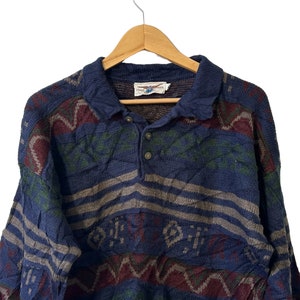 May include: A blue, green, and red patterned sweater with a collared neckline and button closure. The sweater has a striped pattern and a geometric design.