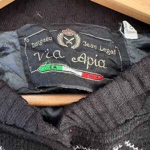 May include: Black and red plaid sweater with a brown button and a label that reads "Designed Via eapia Jean Legal!"