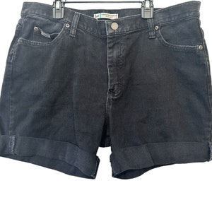 May include: Black denim shorts with a cuffed hem. The shorts have a button and zipper closure and five pockets.