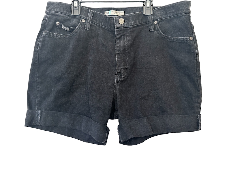 May include: Black denim shorts with a cuffed hem. The shorts have a button and zipper closure and five pockets.