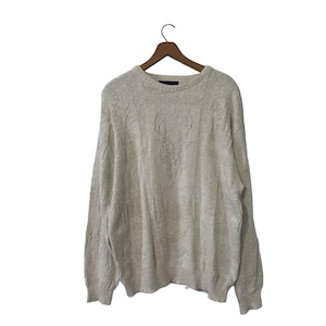 May include: A beige knitted sweater with a textured pattern. The sweater has a crew neck and long sleeves.