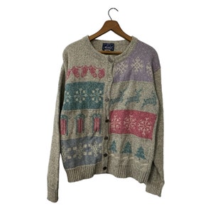 May include: A grey cardigan with a button-up front and a colourful festive pattern. The pattern includes snowflakes, reindeer, and Christmas trees.