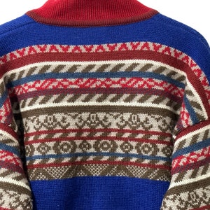 K&ouml;nnte beinhalten: Ein blauer, roter, brauner und wei&szlig;er Pullover mit Muster und hohem Kragen.
