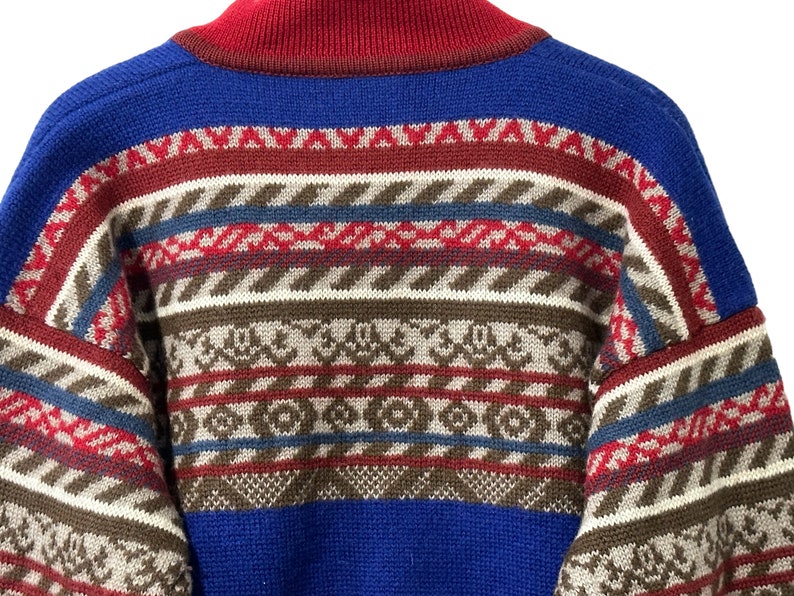 K&ouml;nnte beinhalten: Ein blauer, roter, brauner und wei&szlig;er Pullover mit Muster und hohem Kragen.