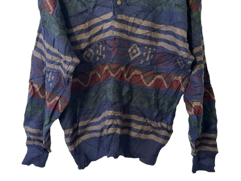 May include: A blue, green, red, and brown patterned sweater with a button closure at the neck.