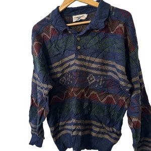 May include: A blue, long-sleeved sweater with a multi-colored geometric pattern. The sweater has a button-up collar and a single button closure.
