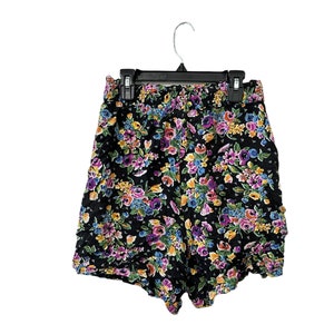 May include: Black floral print shorts with a ruffled hem. The shorts have a drawstring waist and are made of a lightweight fabric.