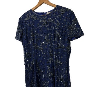 May include: A navy blue sequined dress with a floral pattern. The dress has short sleeves and a round neckline.