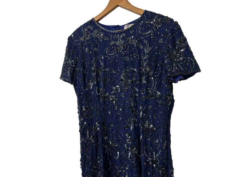 May include: A navy blue sequined dress with a floral pattern. The dress has short sleeves and a round neckline.