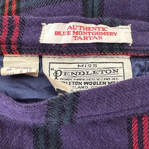 Op de afbeelding: Een paarse, zwarte en rode geruite rok met een wit label waarop "Miss Pendleton" en "Authentic Blue Montgomery Tartan" staat.